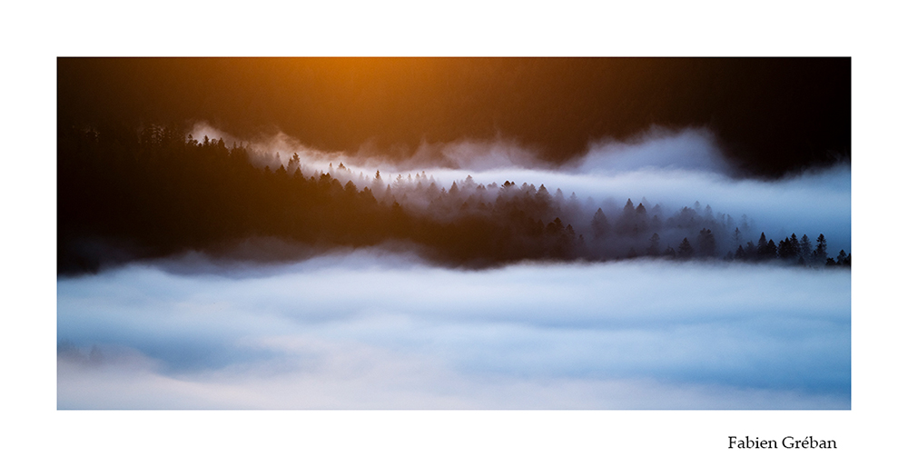 photographie de paysage sur les sommets du massif du Jura au dessus de la mer de nuage, contraste des tons chaud du lever du soleil et des tons froids de la brume dans la valle